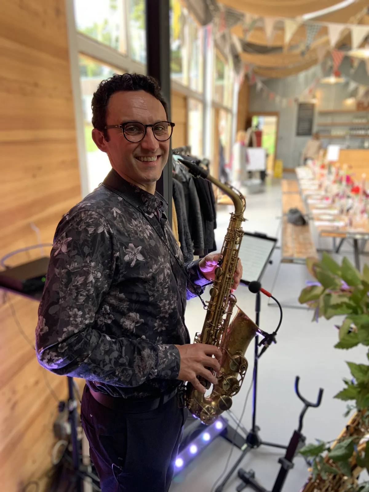 Tom playing saxophone beside a set wedding breakfast table
